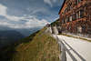 914791_Berggasthaus Jennerbahn holzige Wand Terrasse schöne Bergaussicht Bild mit Touristen in Sonne