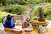 52444_ Kaffeegedeck mit Keksen & Früchten auf Tisch im Garten, Kaffeezeit mit Gartenblick, Kaffeegarten Bild