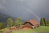 Almhaus Skischule Ossi Bild unter Regenbogen Stimmungsfoto in Sonne nach Gewitter über Alpental Urlaub Reisetip