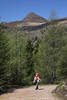 12001764_Rucksacktouristin auf Bergweg Foto unter Gipfel Knoten Alpenlandschaft grüne Bäume Natur Wanderausflug Bild