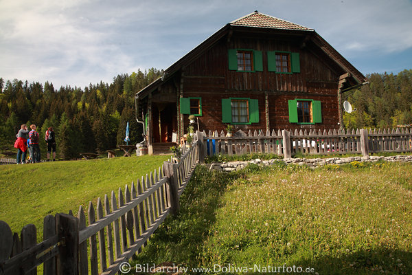Waisacher Almgasthütte Holzhaus grüne Wiese Zaun mit Wanderer