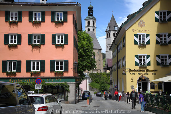Kitzbühel bunte Gasse Café Bar Geschenkstube Hausfenster Farbdesign Kirchtürme im Hintergrund