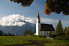 810356_ Tirol Alpen Bergdorf weisses Kirchlein von Mösern Herbstfoto, Landschaft an Dorfwiese vor Berg in Wolken