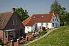 802605_Greetsieler Wohnhuser hinterm Deich Foto im grnen Frhlings Ostfrieslands an Nordseekste