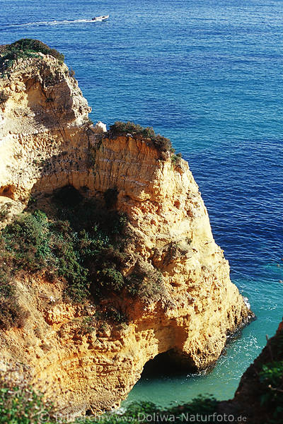 Goldgelber Fels mit Grotte im Meer blau Wasser Algarve Kstenfoto vor Motorboot auf Seefahrt
