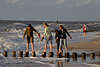 706014_ Mdchen Vierer Barfuss auf Wellenschutzpfahlen vor Gischt der Meerwellen am Seeufer, vier Mdels