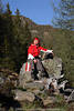 1202067_Frhliches Mdchen Portrts auf Steinsitz lachende Bergwanderer Relax in Natursonne Fotos junge Frau mit Rucksack