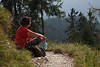 913551_Frau Naturportrt im Rotkleidung am Pfad sitzen, relaxen im Sonnenschein ber grnen Bergwald
