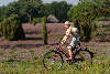 Mdel mit Sonnenhut fahrradfahren vor Heide-Schafstall blond Girl