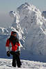 101918_Wintermode: Mdchen dick eingepackt in Winterkleidung Portrt vor weien Tannenriesen in Schnee & Frost