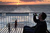 Mann trinkt Bier aus Flasche vor Sonnenuntergang ber Meerhorizont bei Schiffsreise