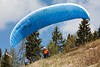 1201050_ Pilot breiten Gleitschirms in Blau am Berghang Startfoto Gleitsegelflieger vor Bumen am Himmel