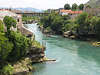 Bd0089_Mostar Bild an Neretva Flusswasser steinige Grnufer Foto Felsen Huser Menschen